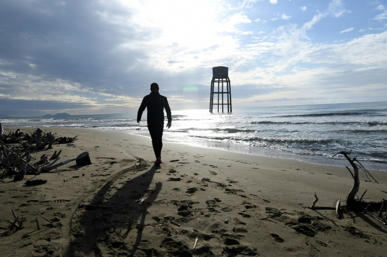 رجل يسير قرب برج مائي مغمور عند ساحل الأدرياتيكي في منطقة سيمان الألبانية في18 نوفمبر2021(ا ف ب)