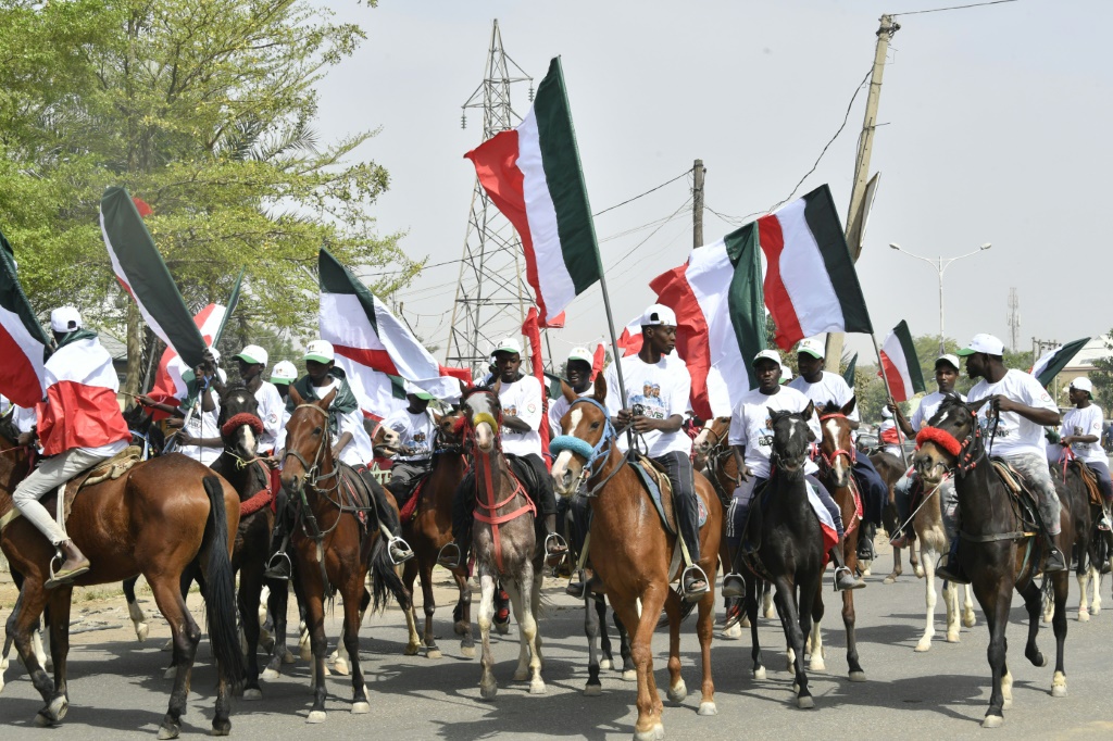    أنصار يلوحون بالأعلام ويمتطون الخيول لحضور تجمع حملة كانو للمرشح أتيكو أبو بكر. (أ ف ب)