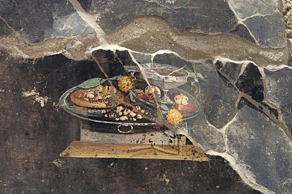 صورة وزعتها إدارة موقع بومبيي الأثري ف الأيطالي في 25 حزيران/يونيو 2023 للوحة جدارية تعود إلى ألفَي عام تمثّل كوب خمرة وما يشبه إلى حد كبير البيتزا (ا ف ب)