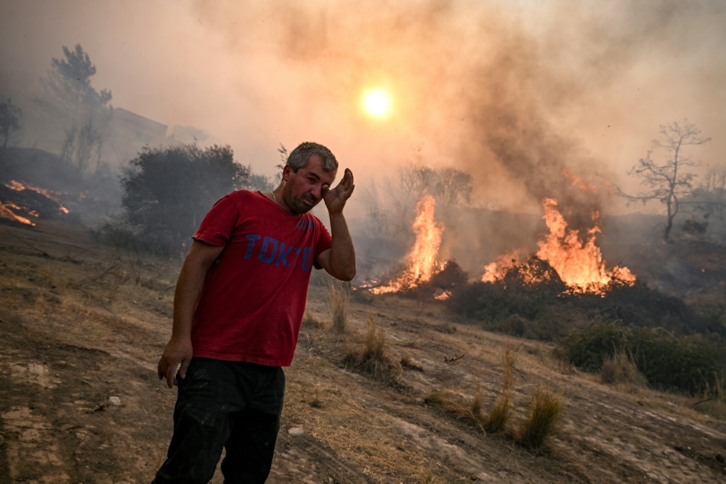 رجل يقف امام حريق في قرية غينادي في جزيرة رودوس اليونانية في 25 تموز/يوليو 2023 (ا ف ب)