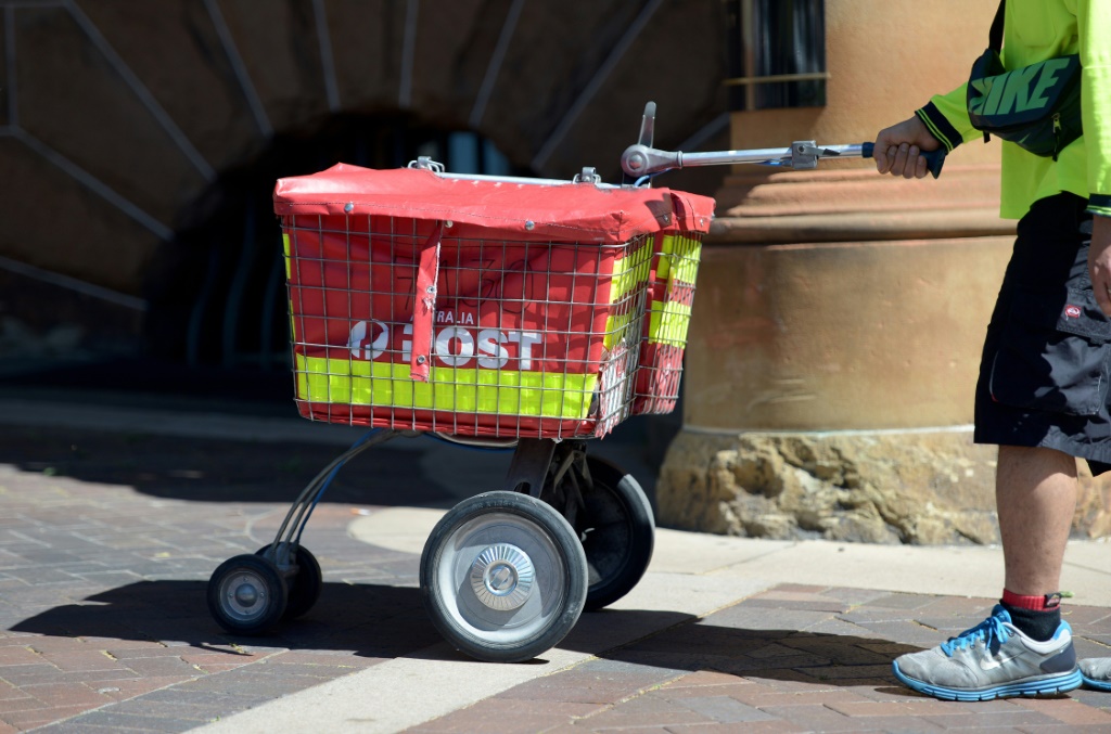 عامل في هيئة البريد الأسترالية ينقل طروداً بريدية في سيدني في 12 أيلول/سبتمبر 2013 (ا ف ب)