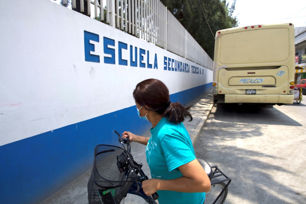 امراة تجر دراجتها الهوائية في جوار مدرسة في مكسيكو اثر احتجاجات على كتب دراسية جديدة (ا ف ب)