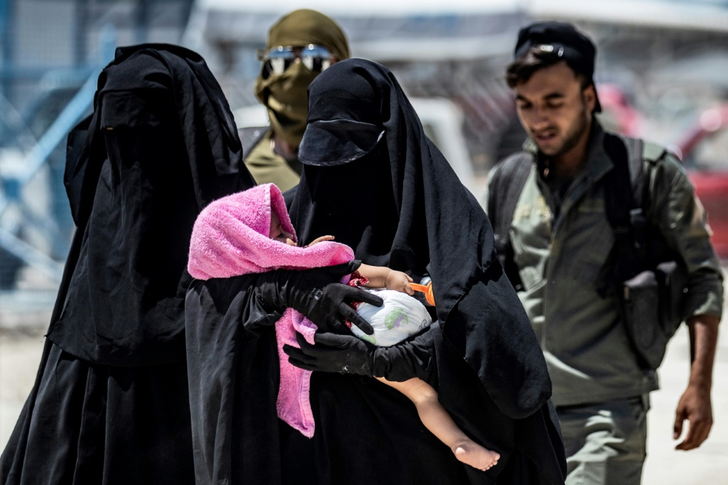 عناصر أمن يصطحبون نساء يعتقد أنهن زوجات مقاتلين في تنظيم الدولة الإسلامية في مخيم الهول في الحسكة بتاريخ 23 تمو/يوليو 2019 (ا ف ب)