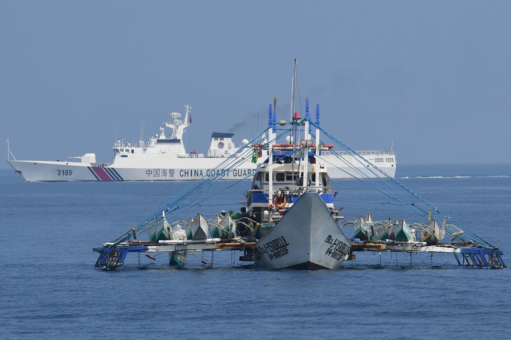 سفينة تابعة لخفر السواحل الصيني خلف سفينة صيد فيليبينية قرب الشعاب المرجانية المتنازع عليها في بحر الصين الجنوبي في 20 ايلول/سبتمبر 2023 (ا ف ب)