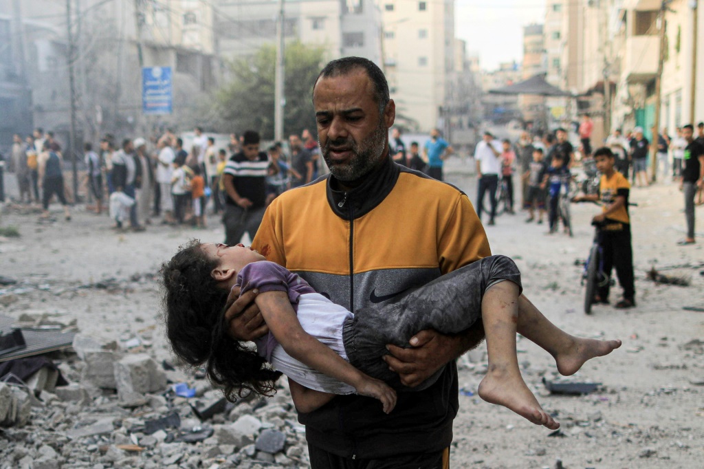 مواطن فلسطيني يحمل أبنته المصابة جراء القصف على غزة من قبل إسرائيل (ا ف ب)