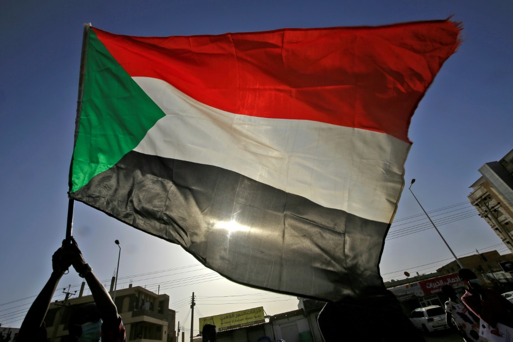 متظاهر سوداني يلوح بالعلم الوطني في منطقة الرياض شرق العاصمة الخرطوم في 3 حزيران/يونيو 2020 (ا ف ب)