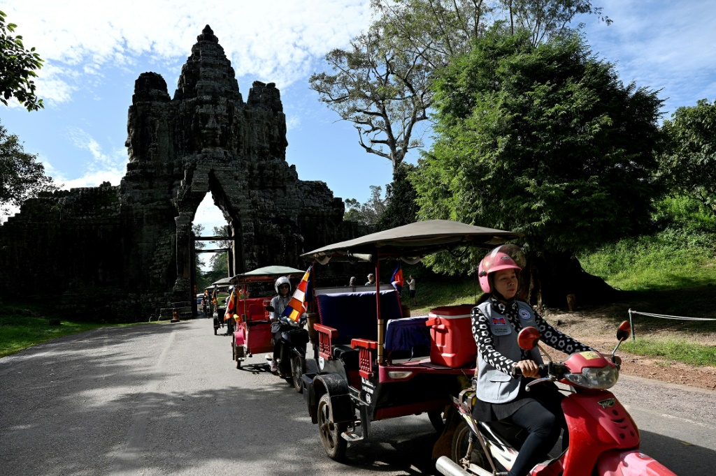 سائقات التوك توك يمررن عبر البوابة الجنوبية لأنغكور ثوم في مجمع أنغكور في مقاطعة سيام ريب (ا ف ب)   