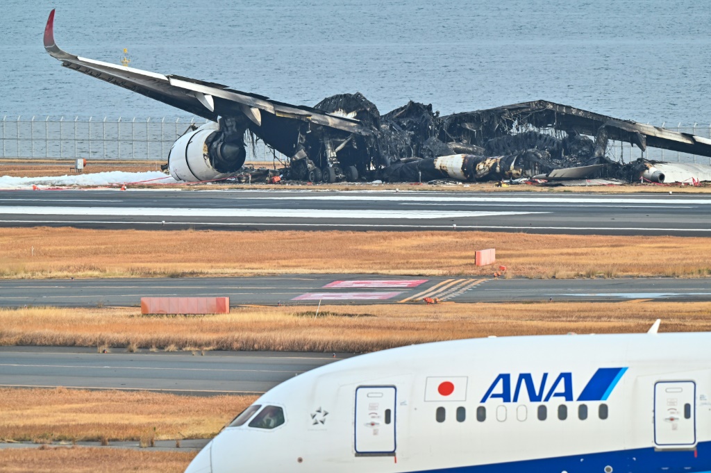 حطام طائرة ركاب تابعة للخطوط الجوية اليابانية محترق على مدرج مطار هانيدا بطوكيو (ا ف ب)
