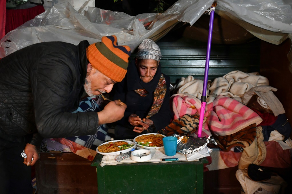 ليلى ومشرد آخر يتشاركان طعاماً حصلا عليه في إطار مبادرة "مطعم الحب" لمساعدة المشردين، في تونس العاصمة في 26 كانون الثاني/يناير 2024 (أ ف ب)   