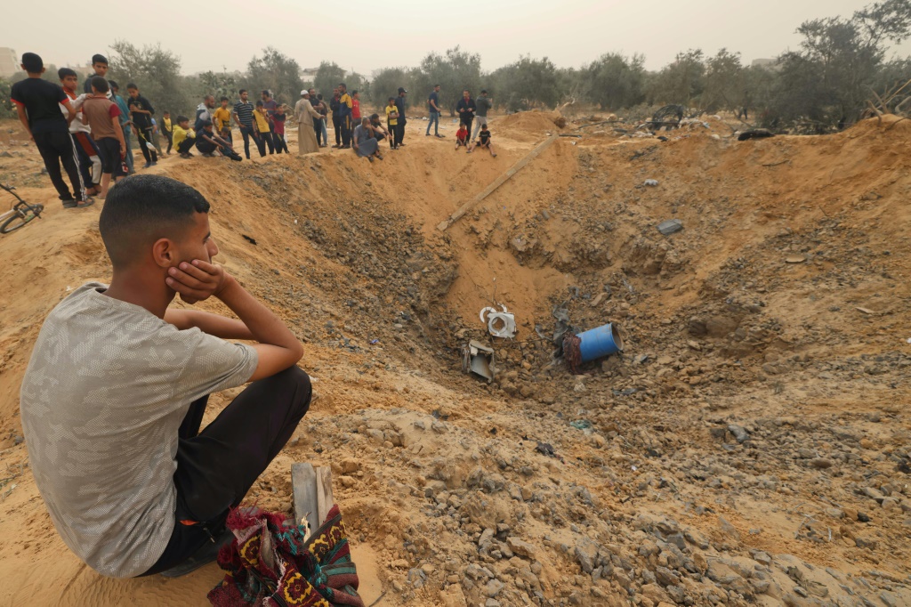    فلسطينيون يتجمّعون في 18 نيسان/أبريل 2024 حول حفرة كبيرة بعد غارة إسرائيلية في رفح جنوب قطاع غزة (أ ف ب)   