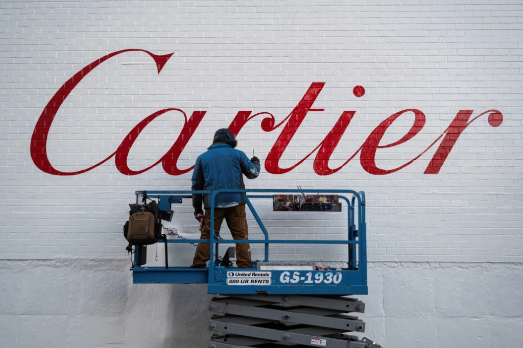 عامل يرسم شعار شركة كارتييه الفرنسية على أحد الجدران في نيويورك بتاريخ 8 كانون الثاني/يناير 2024 (ا ف ب)