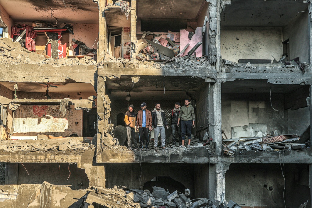 فلسطينيون يتفقدون مبنى شبه مدمر عقب قصف إسرائيلي في رفح جنوب قطاع غزة في 15 كانون الأول ديسمبر 2023 (ا ف ب)
