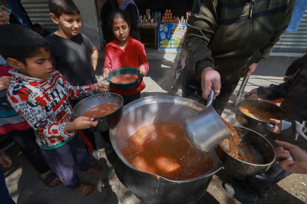 أطفال فلسطينيون يحصلون على الطعام في إطار مبادرة شبابية تطوعية في رفح بجنوب قطاع غزة، في 5 آذار/مارس 2024، وسط انتشار الجوع في القطاع المحاصر (أ ف ب)   