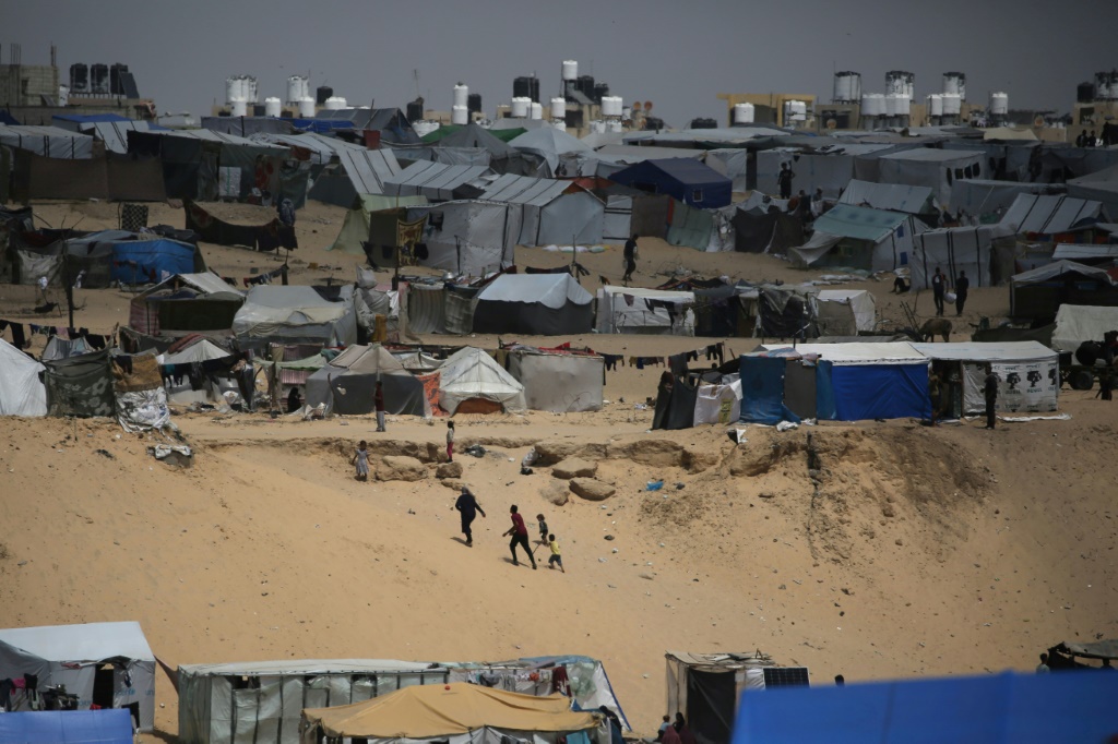 فلسطينيون يسيرون في مخيم للنازحين في رفح في أقصى جنوب قطاع غزة قرب الحدود مع مصر في 28 نيسان/أبريل 2024 (ا ف ب)