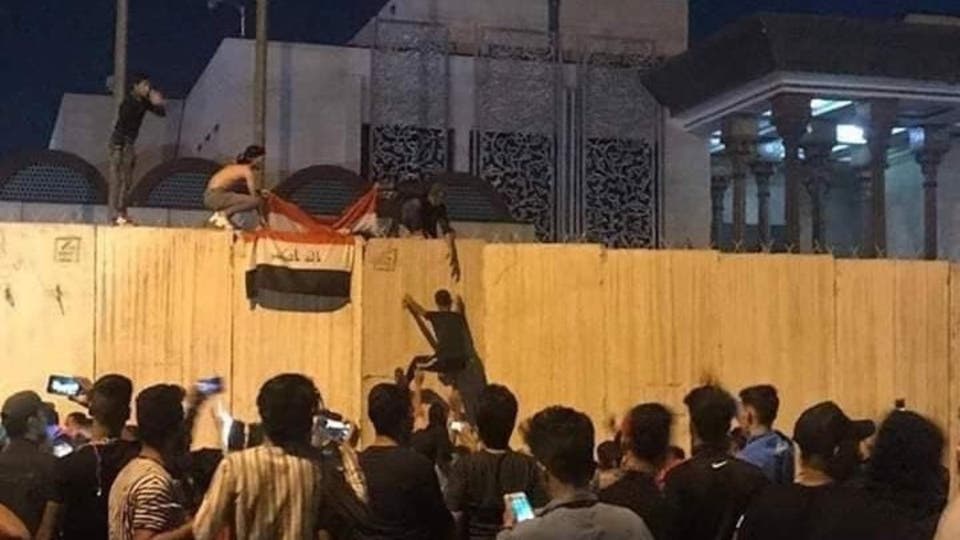 متظاهرون عراقيون يرفعون علم بلادهم على قنصلية إيران بكربلاء