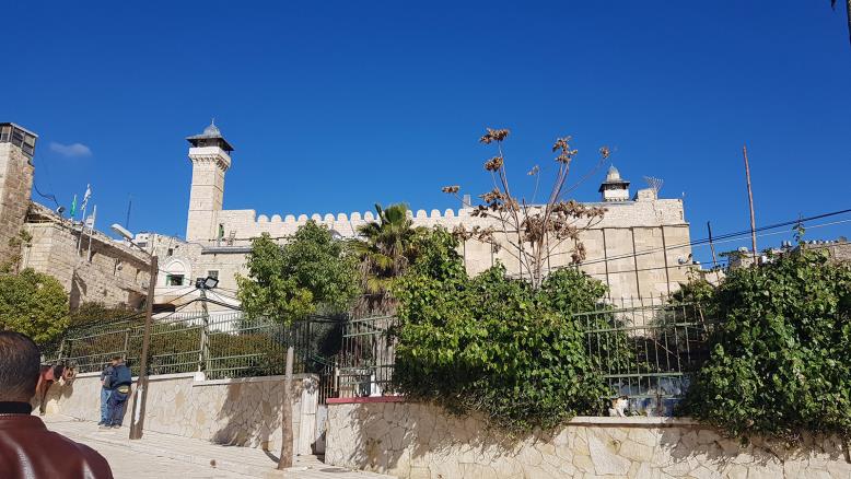  أقصى يمين المسجد شمعدان نصبه المستوطنون فوق المسجد الإبراهيمي وإلى اليسار أعلام الاحتلال وجيشه (الجزيرة)
