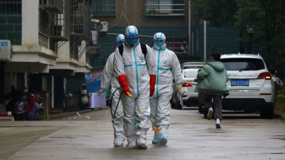 رجال يلبسون سترات واقية في أحد شوارع الصين (رويترز)