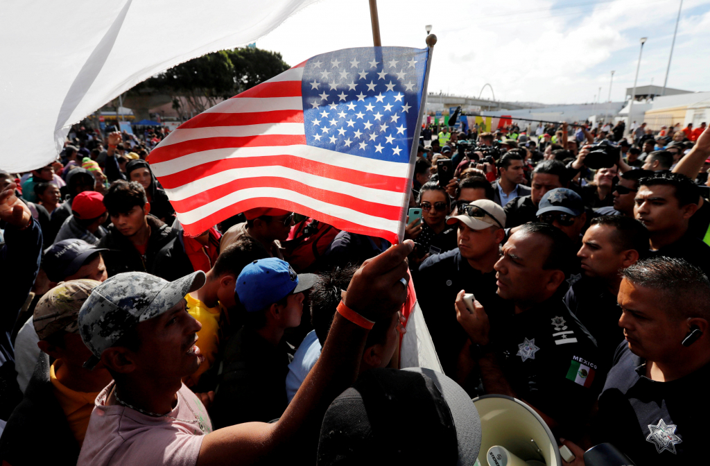  مهاجرون يحملون علم أميركا عند حدودها مع المكسيك