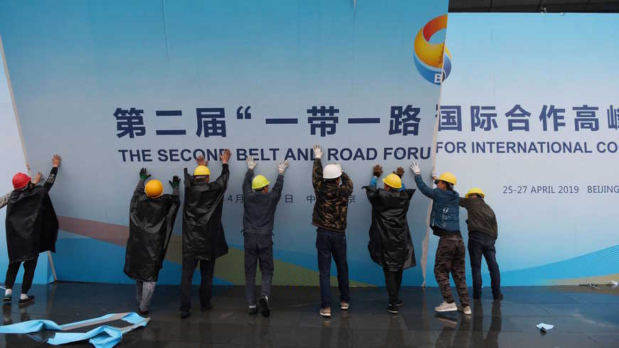 عمال يزيلون لوحة لمنتدى الحزام والطريق الذي عقد في بكين في 27 أبريل 2019