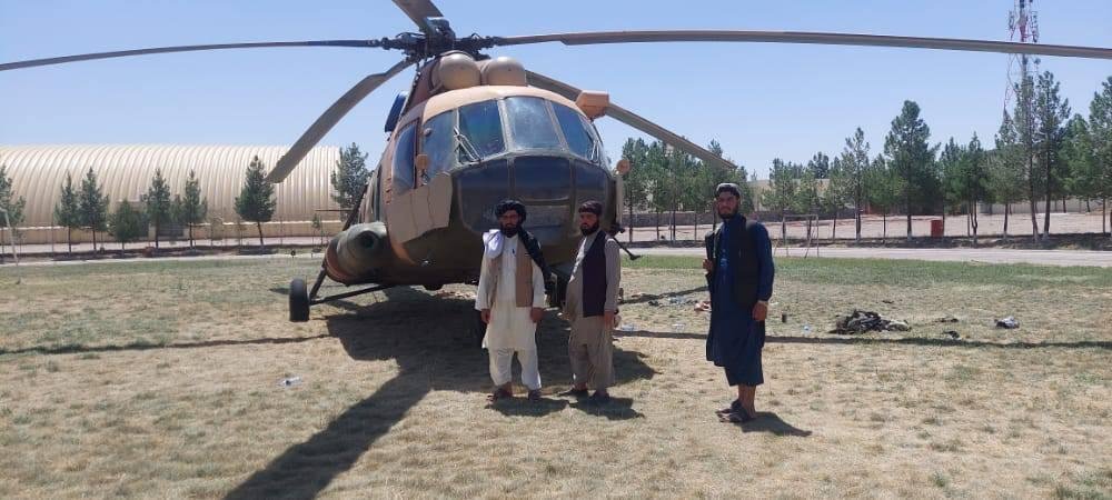 مقاتلون من حركة طالبان يقفون بجانب مروحية تم اغتنامها من الجيش الأفغاني المنهار في ولاية هرات غرب أفغانستان