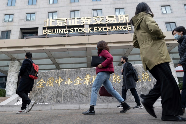 أشخاص يمرون من أمام بورصة بكين في اليوم الأول للتداول بتاريخ 15 تشرين الثاني/نوفمبر 2021(ا ف ب)