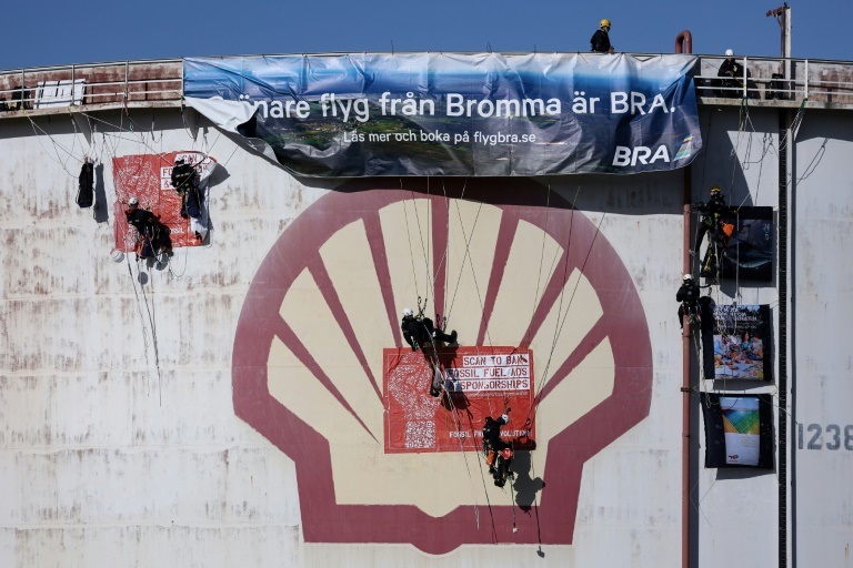 نشطاء من منظمة السلام الأخضر غير الحكومية البيئية يتسلقون صهريج تخزين لتعليق لافتة في مصفاة شركة شل الهولندية للنفط في ميناء روتردام في 4 تشرين الأول/أكتوبر 2021 (ا ف ب)