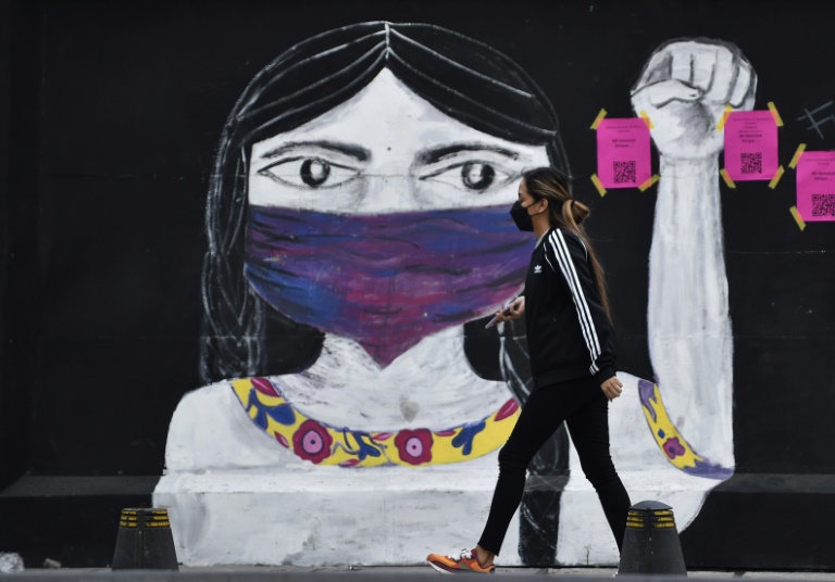 امرأة تسير أمام الكتابة على الجدران قبل مظاهرة للاحتفال باليوم الدولي للقضاء على العنف ضد المرأة في مكسيكو سيتي (ا ف ب)