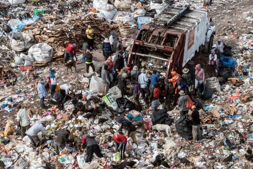   لقطة جوية لأشخاص يبحثون في القمامة عن قطع بلاستيكية أو معدنية لبيعها في مكب نفايات البلدية في ضواحي تيغوسيغالبا (أ ف ب)
