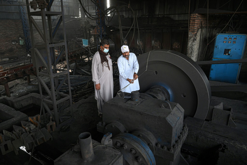 عضوان في كتيبة مكافحة تلوث الهواء يتأهبان لإغلاق مصنع مخالف في مدينة لاهور الباكستانية في 19 تشرين الثاني/نوفمبر 2021 (أ ف ب)