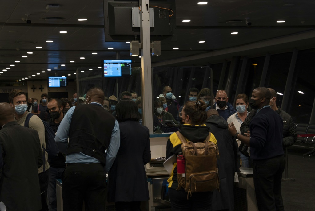 يحتشد المسافرون في مطار جوهانسبرج الدولي ، في أمس الحاجة إلى اللحاق برحلاتهم الأخيرة إلى البلدان التي فرضت حظراً مفاجئاً على السفر (أ ف ب)