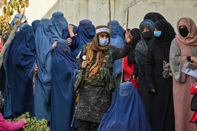 مقاتل من طالبان يحافظ على النظام بينما تنتظر النساء في طابور خلال توزيع برنامج الأغذية العالمي في كابول(ا ف ب)