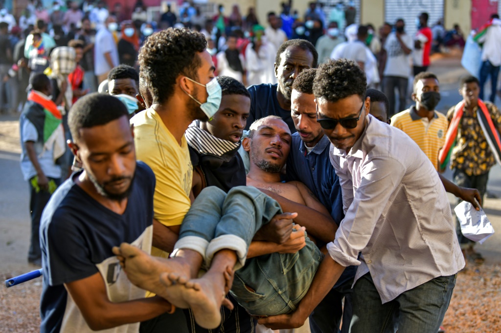 إبعاد متظاهر سوداني جريح مناهض للانقلاب خلال مظاهرة في مدينة أم درمان بالعاصمة (أ ف ب)   