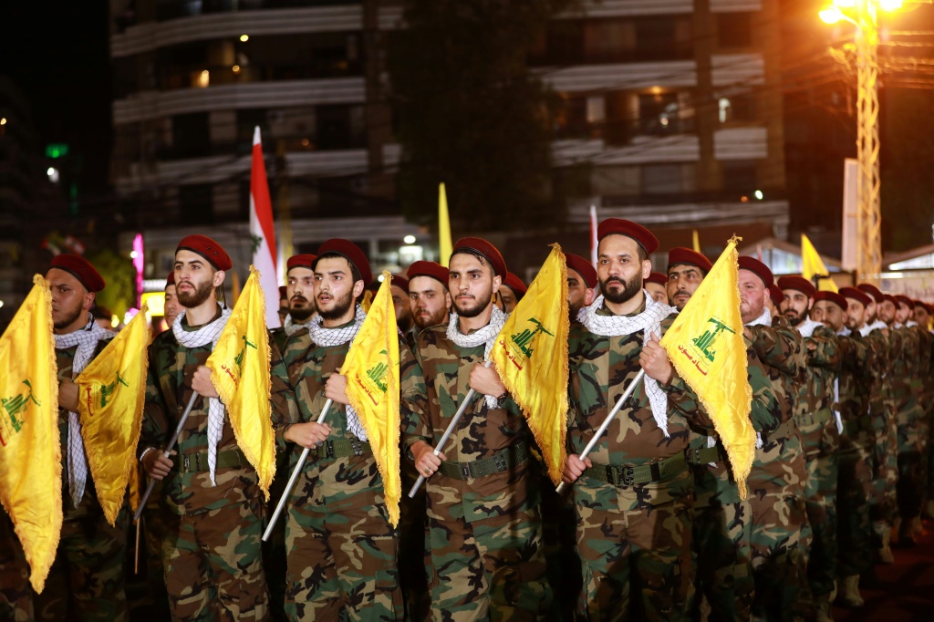   عناصر من حزب الله الشيعي يرفعون الأعلام أثناء استعراضهم في الضاحية الجنوبية للعاصمة اللبنانية بيروت (أ ف ب)