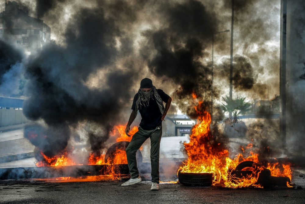  بيروت: رجل يسير عبر إطارات مشتعلة تسد طريقا سريعا رئيسيا   احتجاجا  ضد الظروف الاقتصادية   (د ب أ)