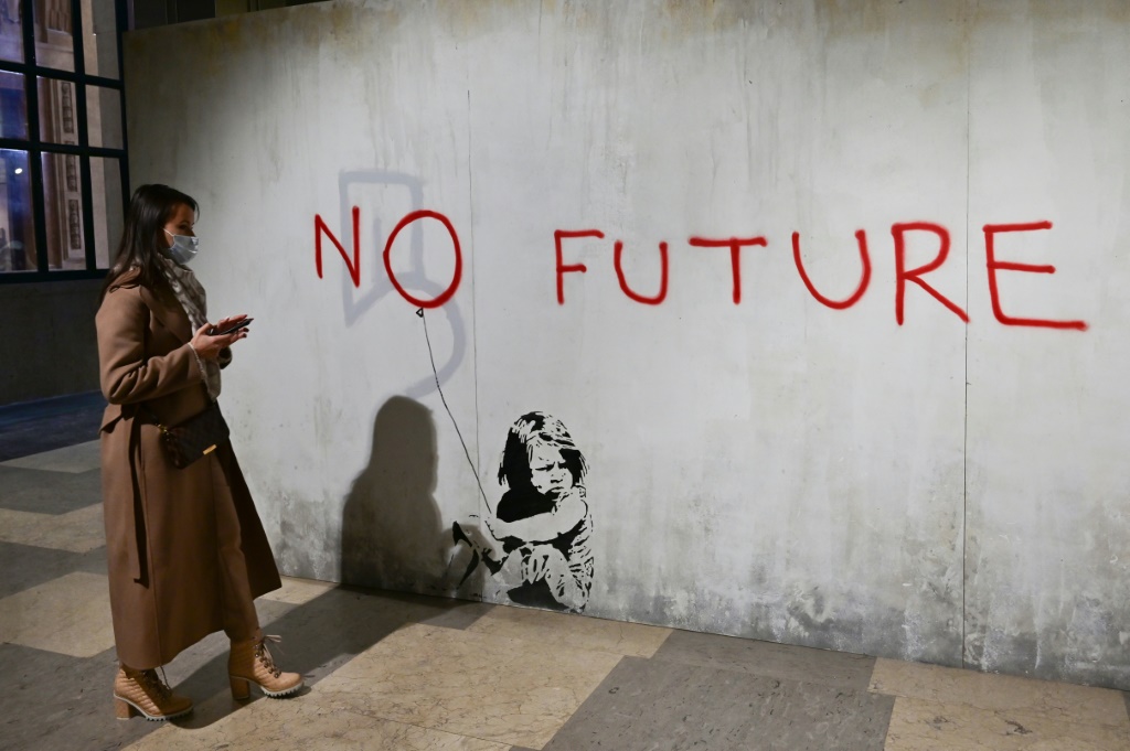 امرأة ننظر في 2 كانون الأول/ديسمبر 2021 إلى أحد أعمال فنان الشارع البريطاني بانكسي ضمن معرض "عالم بانكسي" في محطة ميلانو للقطارات (أ ف ب)