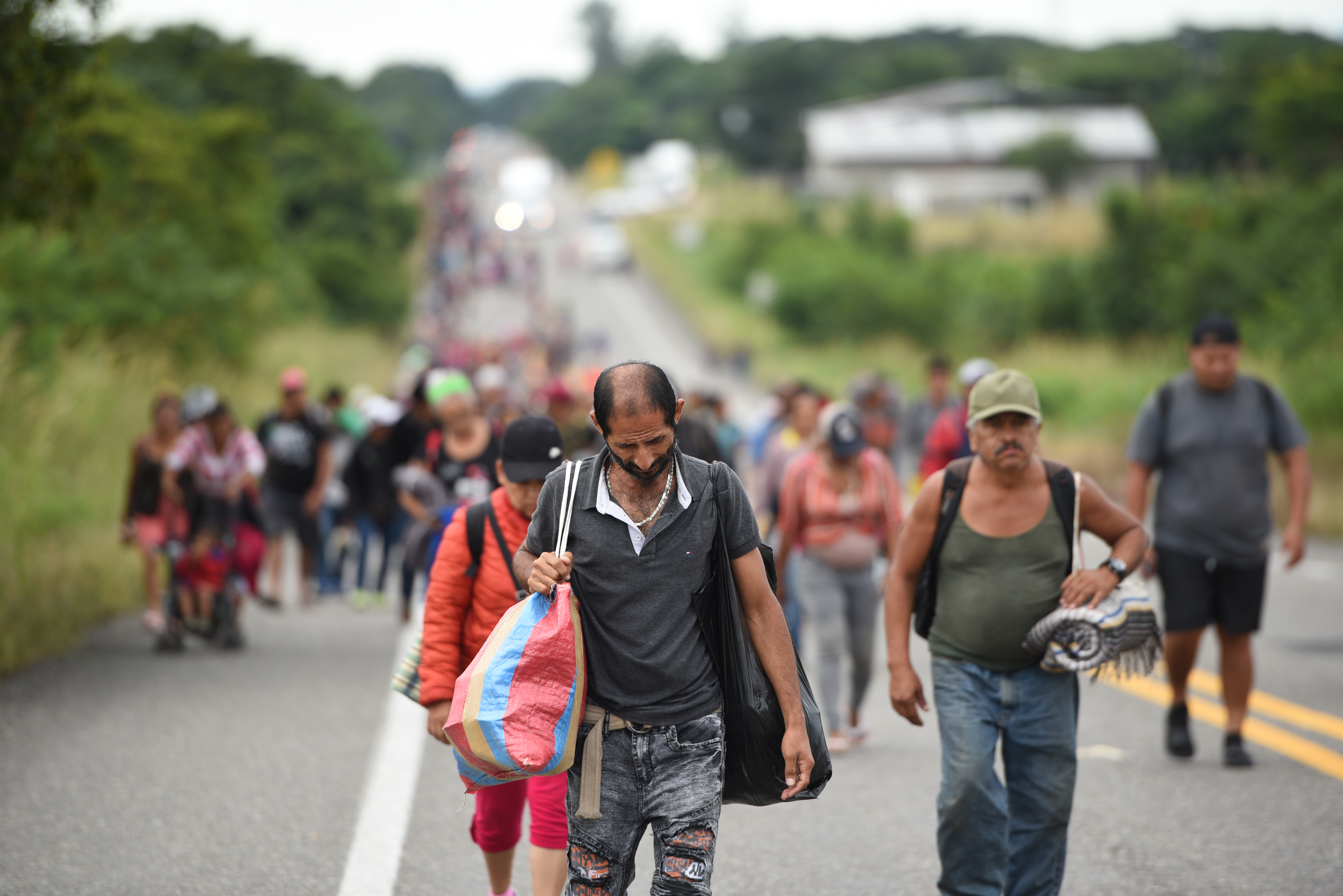 العديد من الناس من أمريكا الوسطى يسيرون معا على طول الطريق الريفي نحو الحدود الأمريكية(د ب أ)