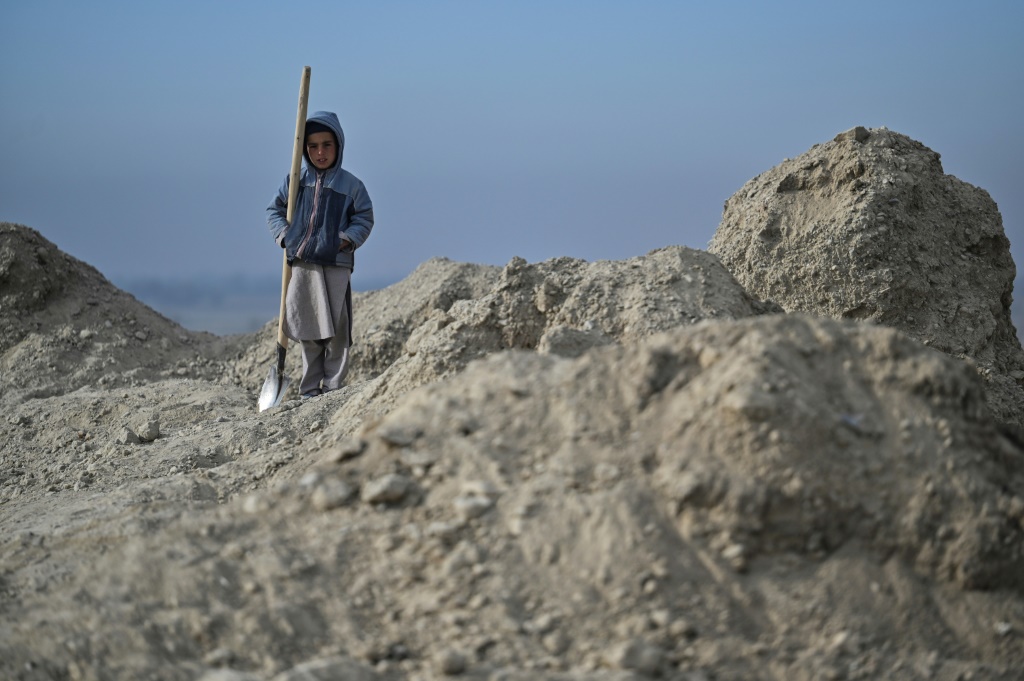 فتى يحمل رفشا قرب أنقاض منزل مهدو في قرية آرزو بجنوب أفغانستان في 16 تشرين الثاني/نوفمبر 2021 (ا ف ب)
