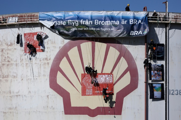 نشطاء من منظمة السلام الأخضر غير الحكومية البيئية يتسلقون صهريج تخزين لتعليق لافتة في مصفاة شركة شل الهولندية للنفط في ميناء روتردام في 4 تشرين الأول/أكتوبر 2021(أ ف ب)