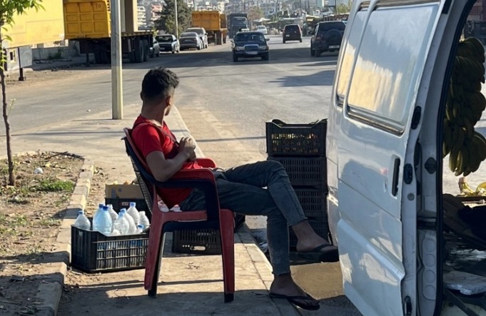 أحمد مواس (14 عاما) يعمل 12 ساعة يوميا لبيع محصول صاحب الحافلة (الجزيرة)