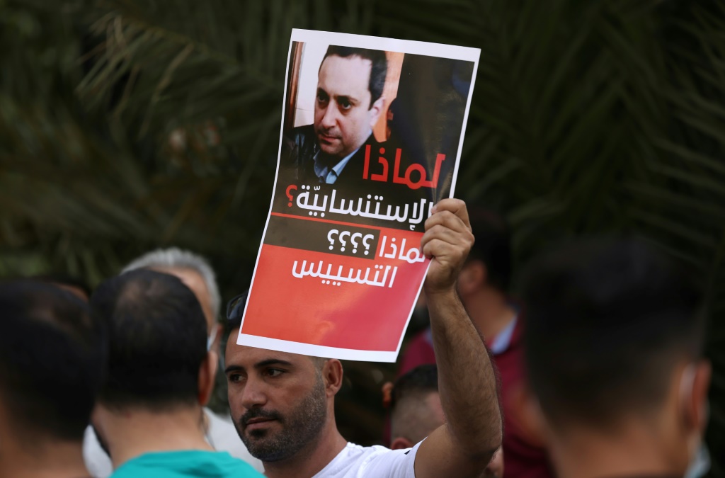 لافتة تحمل صورة القاضي طارق بيطار المحقق العدلي في انفجار مرفأ بيروت، يرفعها متظاهر معارض للقاضي في العاصمة اللبنانية بتاريخ 14 تشرين الأول/أكتوبر 2021 (أ ف ب)   