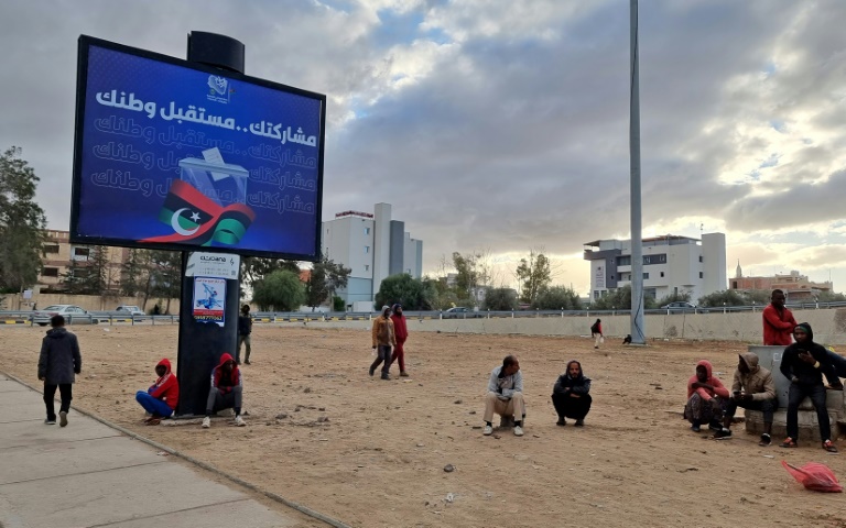 ليبيون قرب لوحة انتخابية في طرابلس في 14 كانون الأول/ديسمبر 2021(ا ف ب)   