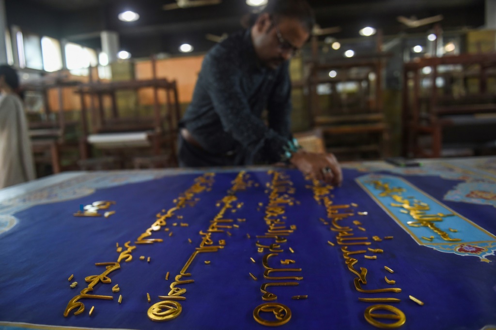 فنان باكستاني يعمل على مشروع كتابة آيات قرآنية ذهبية بالخط العربي في مدينة كاراتشي (ا ف ب)