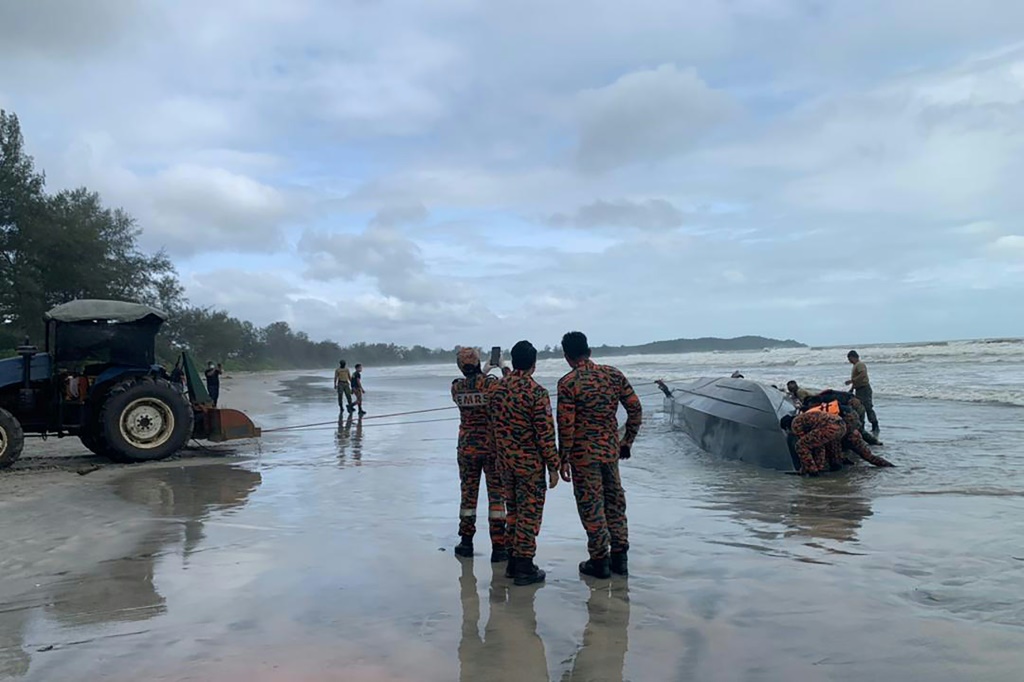 جنود ماليزيون يحضرون القارب إلى الشاطئ بعد أن انقلب قبالة سواحل جوهور (أ ف ب)