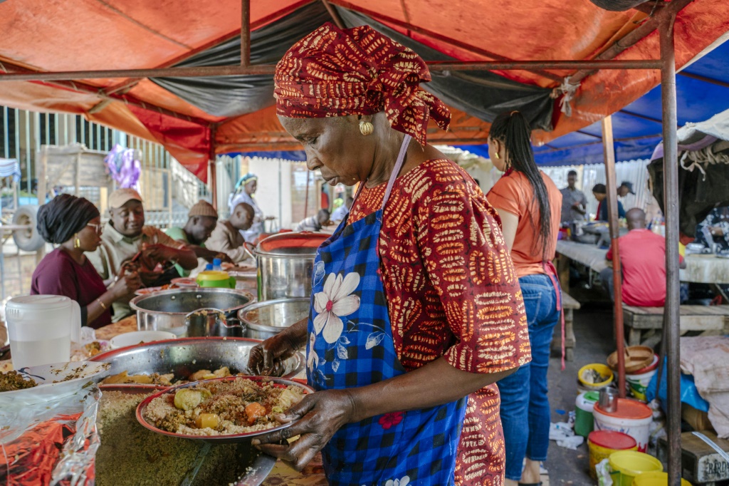 امرأة تقدّم طبق "تشيبو جين" في سوق كيرميل في داكار في 14 ديسمبر 2021 (ا ف ب)