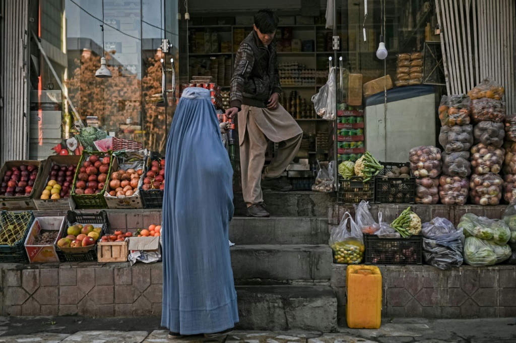 امرأة ترتدي البرقع تشتري البقالة من متجر في كابول ، حيث أدت أزمة اقتصادية إلى ارتفاع الأسعار(أ ف ب)