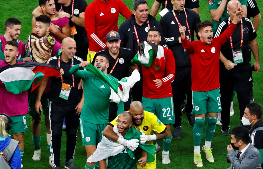 لاعبو المنتخب الجزائري يلوحون لعلم فلسطين بعد الظفر بلقب كأس العرب (ا ف ب)
