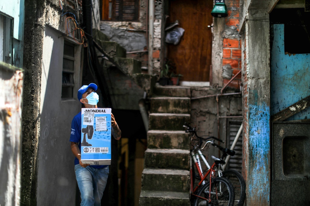 موظّف في "فافيلا برازيل إكسبرس" يحمل طرداً سيُسلّم إلى أحد سكّان حيّ بارايسوبوليس الشعبي في ساو باولو - البرازيل في 1 كانون الأول/ديسمبر 2021 (أ ف ب)