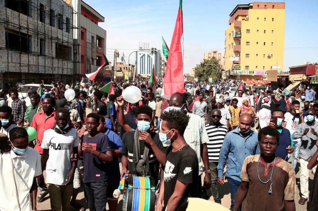 شبان سودانيون يرفعون أعلاما وطنية في تظاهرة ضد الحكم العسكري في العاصمة الخرطوم في 19 كانون الأول/ديسمبر 2021 (ا ف ب)