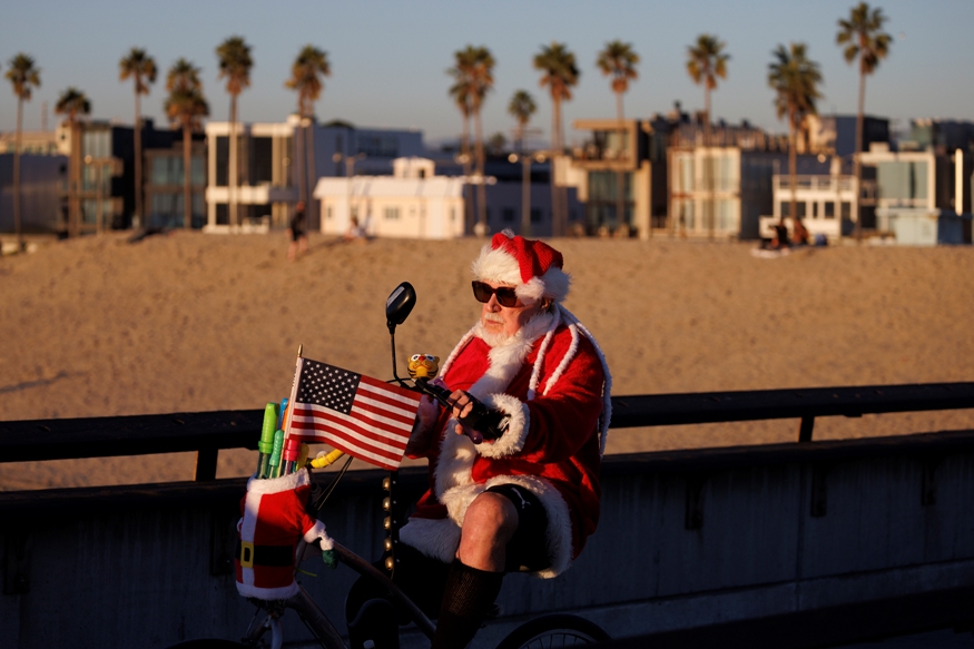 رجل يرتدي زي بابا نويل يقود دراجته على رصيف فينيسيا في لوس أنجلوس بكاليفورنيا (د ب أ)