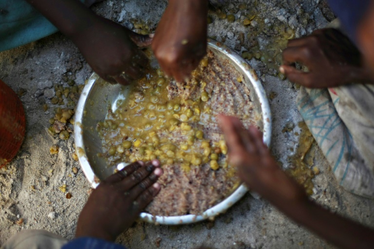 أطفال لاجئون يتشاركون وجبة طعام في مخيّم في الصومال(ا ف ب  )